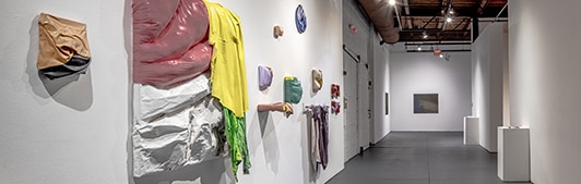 Sculptures hanging on a white wall.