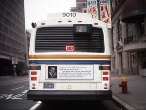 Bus driving through Hartford. On the bus is the Group Material "AIDS Bus Poster".