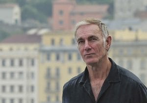 John Sayles standing in front of a cityscape.