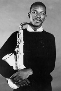 Ornette Coleman smiling and holding a saxophone.