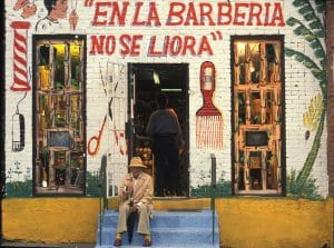 Barbershop store front installation by Pepon. Red text" En La Barberia No Se Llora".