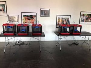 Two tables with 3D printers in the middle of Real Arts Ways gallery