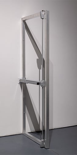 An aluminum doorframe with panic bar hardware, mounted to a gallery wall.
