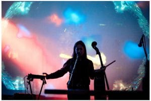 a woman holding a cello in front of a lighted background