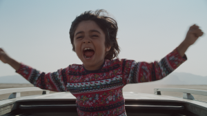 a child exclaiming out of the sunroof of a car