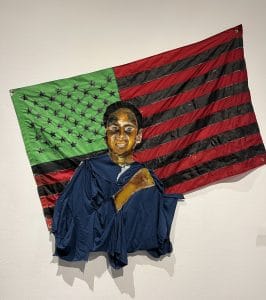 Traé's art. a boy in tatters hanging up against an American flag. 