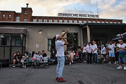 A man singing into a microphone pointing to the sky.