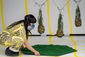 an artist performing at their exhibition with pineapples