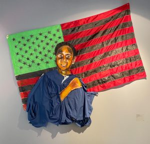 an underrepresented boy standing in front of an American flag