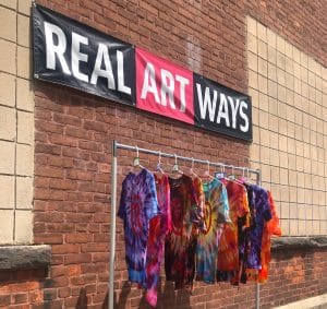 tie-dye shirts hanging on a clothes rack outside