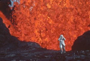 A person standing in front of a volcanic explosion.