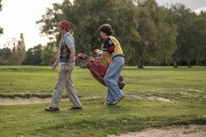 A golf caddy walking after the film's lead character