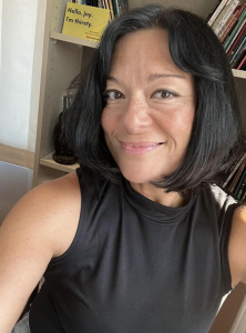 A woman standing in front of a bookcase. 