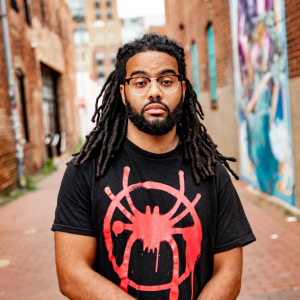 A man with a beard standing in an alleyway.