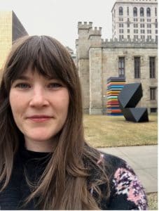 A woman with bangs standing in front of a building.