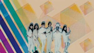 A group of six musicians all in white standing in front of a psychedelic background