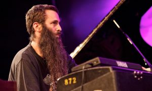 A man with a long beard playing the piano.