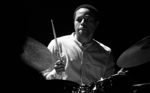 A black and white image of a man playing the drums.
