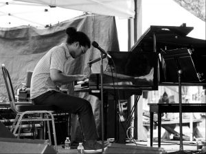 A black and white image of a person sitting and playing the piano.