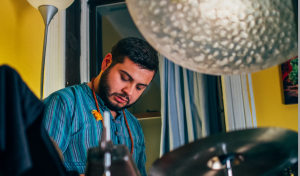 A man sitting and playing a drum set.