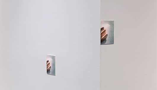 A gallery corner with two similar images of hands