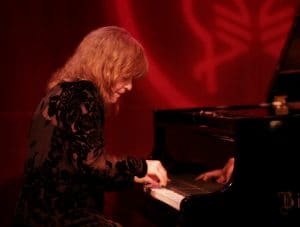 A woman playing the piano on a stage.