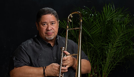 A headshot of a man holding a trombone.