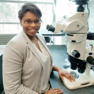 Dr. Heather Bennett sitting at a microscope in a lab.